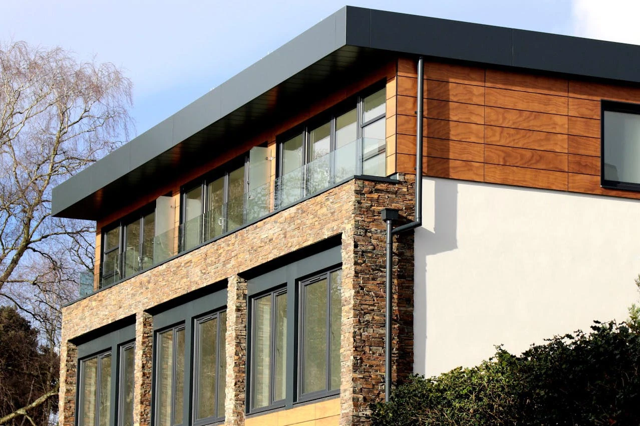 Exterior view of a modern stone home with natural stone facade and large glass windows