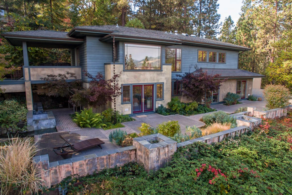 Modern stone home with glass and stone facade surrounded by trees